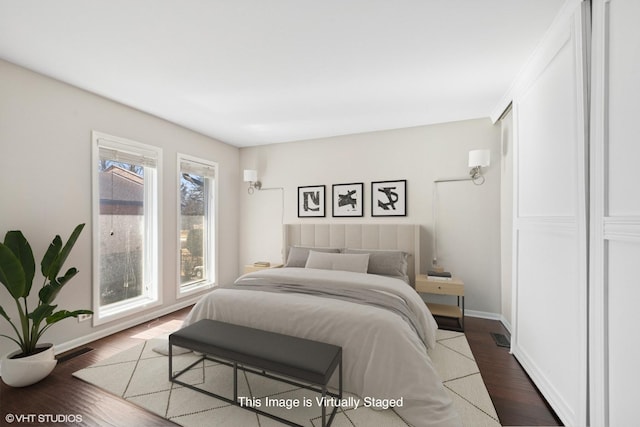 bedroom with dark wood finished floors, visible vents, and baseboards