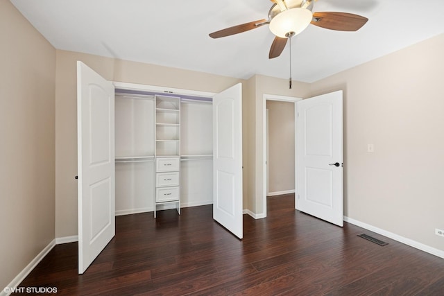 unfurnished bedroom with a closet, dark wood finished floors, visible vents, and baseboards