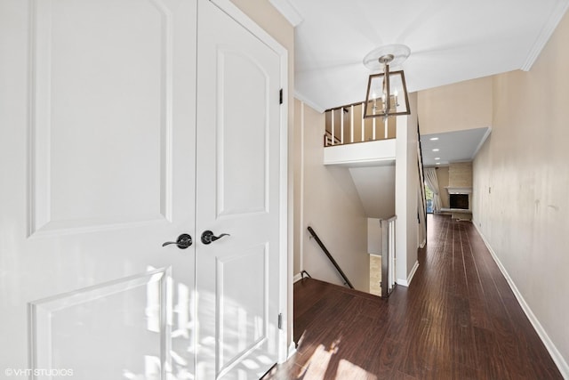 corridor featuring baseboards, wood finished floors, an inviting chandelier, crown molding, and an upstairs landing