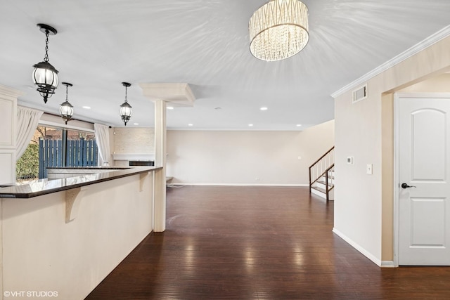 kitchen with dark wood-style floors, visible vents, a breakfast bar, and crown molding