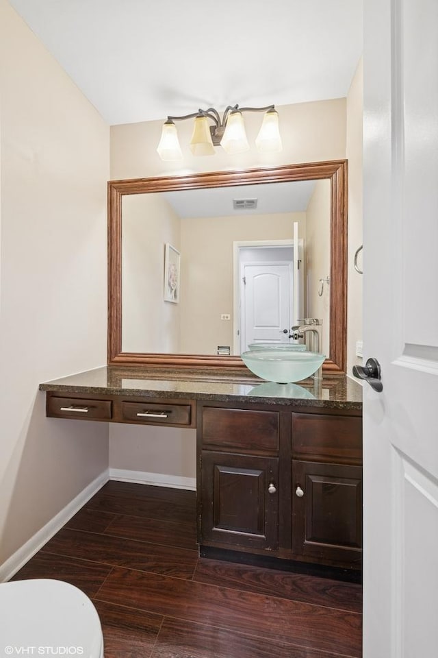 bathroom featuring baseboards, visible vents, toilet, wood finished floors, and vanity