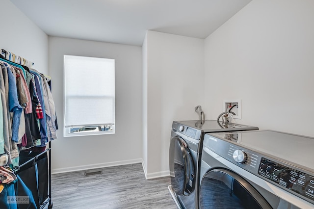 clothes washing area featuring visible vents, separate washer and dryer, wood finished floors, laundry area, and baseboards