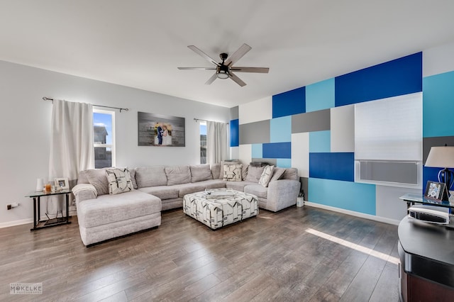 living room featuring an accent wall, baseboards, dark wood finished floors, and a ceiling fan