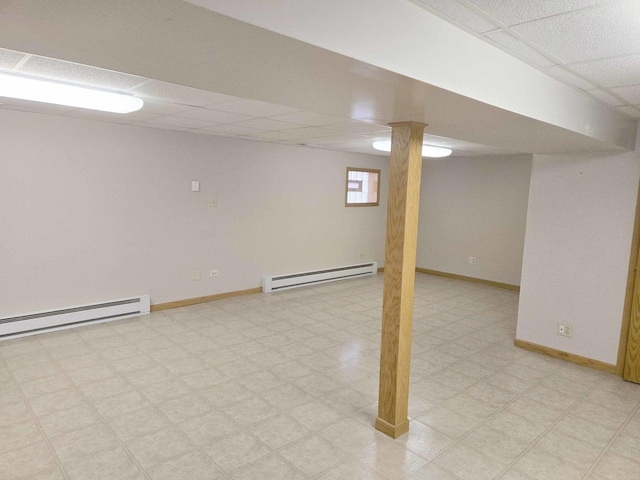 basement featuring light floors, baseboards, a drop ceiling, and baseboard heating