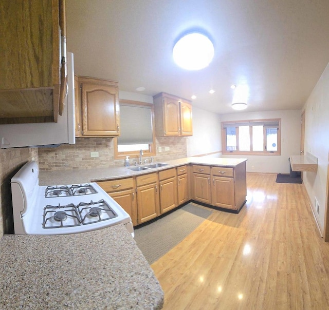 kitchen featuring light countertops, white gas range, a sink, and a peninsula