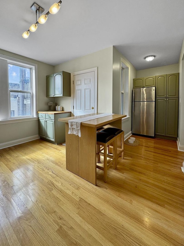 kitchen featuring light countertops, light wood finished floors, freestanding refrigerator, and baseboards