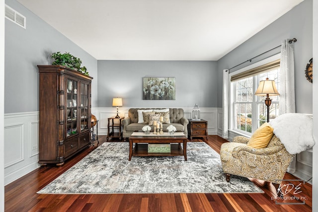 living area with dark wood-type flooring, wainscoting, and visible vents