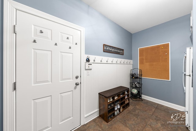 doorway to outside with a wainscoted wall and baseboards