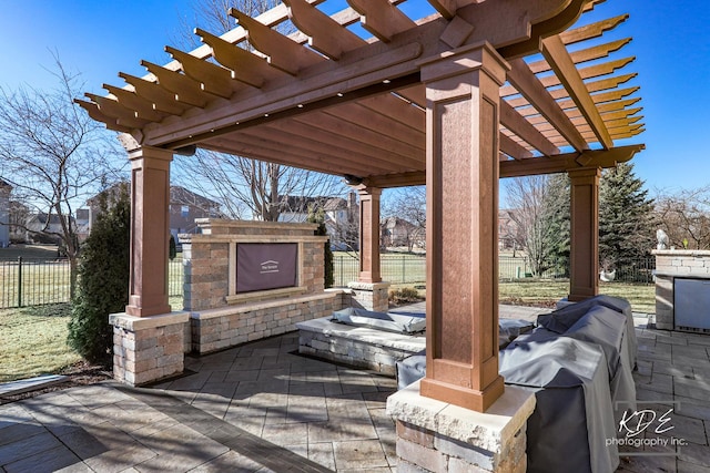 view of patio featuring fence, exterior fireplace, and a pergola