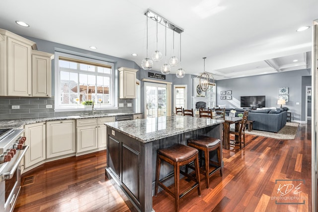 kitchen with dark wood-style floors, stainless steel stove, open floor plan, a kitchen island, and a kitchen bar