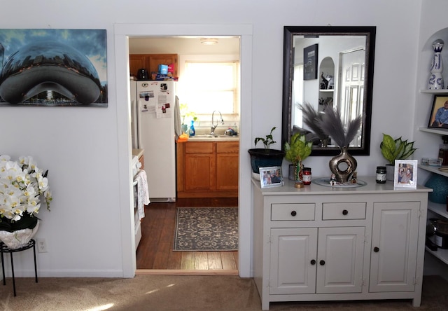 bar featuring dark wood-type flooring, a sink, and freestanding refrigerator