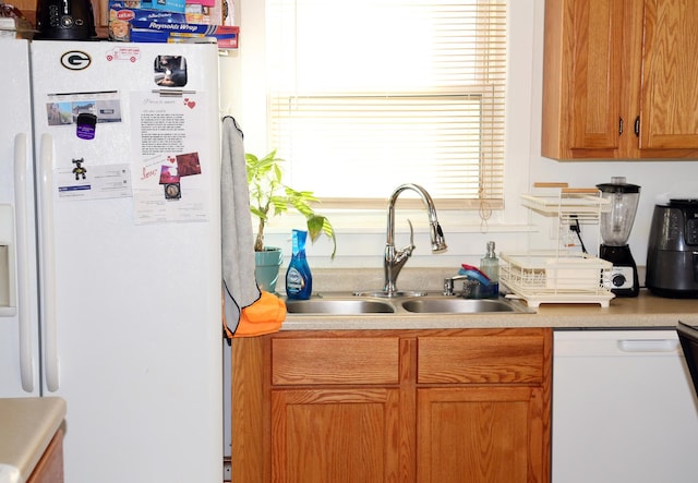 kitchen with light countertops, white appliances, brown cabinets, and a sink