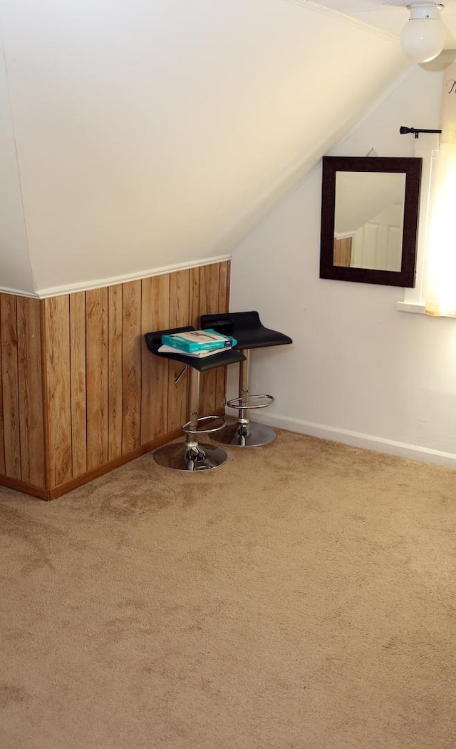 additional living space featuring lofted ceiling, wood walls, baseboards, and carpet flooring