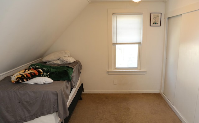 carpeted bedroom with vaulted ceiling and baseboards