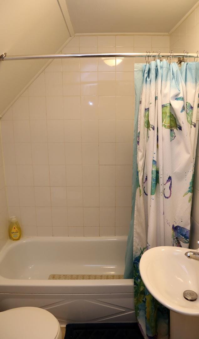 bathroom featuring a sink, toilet, and shower / tub combo with curtain