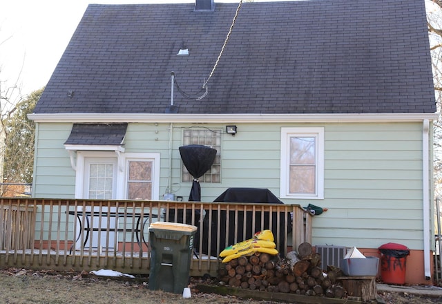 rear view of house featuring roof with shingles and a wooden deck