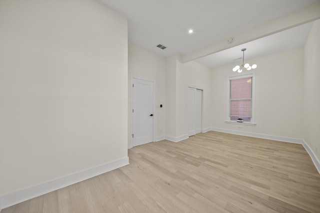 unfurnished room featuring light wood finished floors, baseboards, visible vents, and a notable chandelier