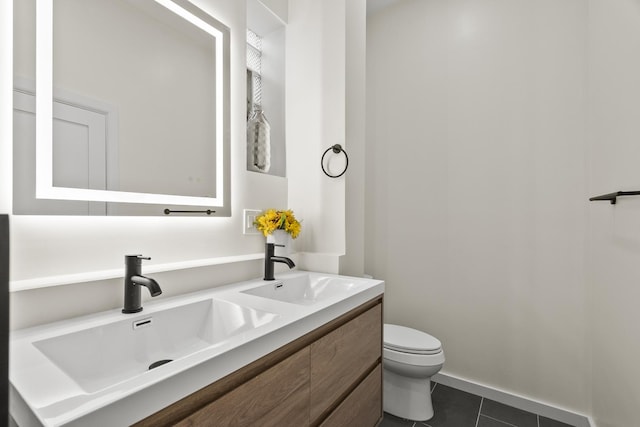 bathroom with double vanity, tile patterned flooring, a sink, and toilet