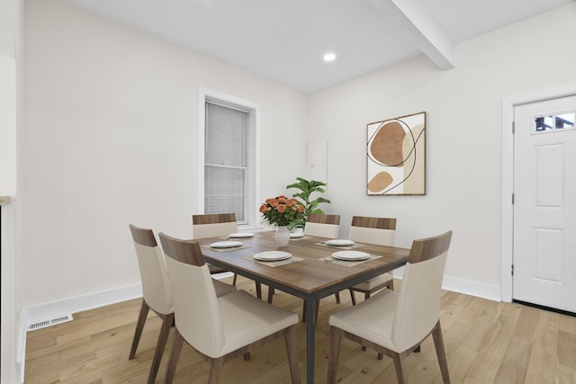 dining area featuring light wood-type flooring, beam ceiling, visible vents, and baseboards