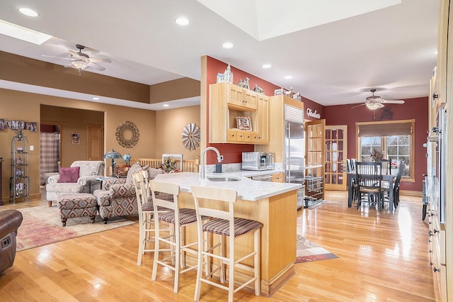 kitchen with light wood-style floors, light brown cabinets, appliances with stainless steel finishes, and a sink