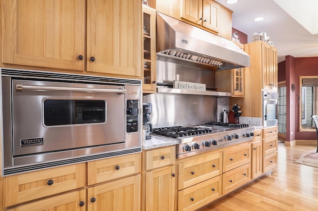 kitchen with under cabinet range hood, stainless steel appliances, light wood finished floors, and light brown cabinetry