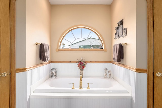 bathroom featuring a wainscoted wall and a garden tub