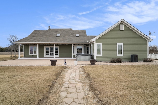 rear view of house with a patio area, a hot tub, a shingled roof, and a lawn