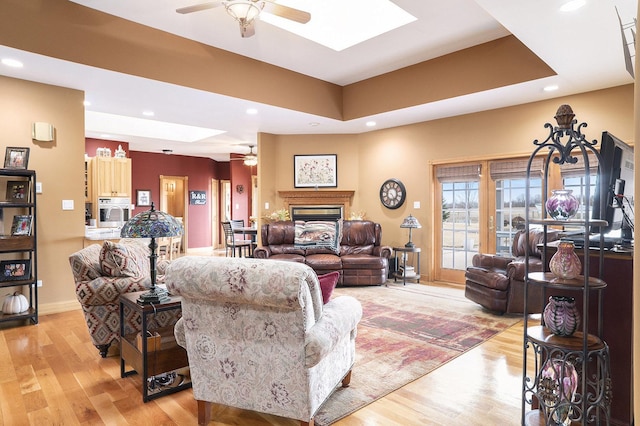 living area with light wood-style floors, a fireplace, a skylight, and recessed lighting