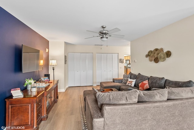 living area with light wood-style flooring and a ceiling fan