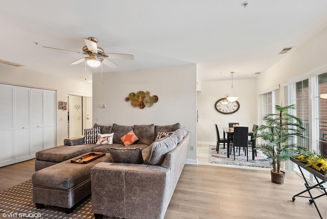 living area featuring a ceiling fan, visible vents, and light wood-style floors