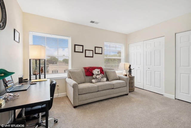 office area with light carpet, a wealth of natural light, visible vents, and baseboards