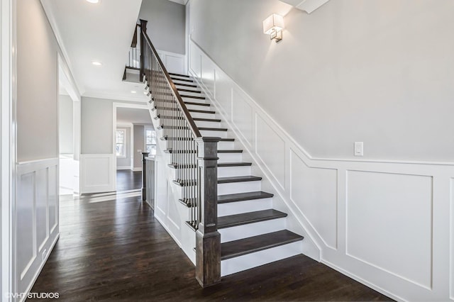 stairs featuring recessed lighting, a decorative wall, wood finished floors, ornamental molding, and wainscoting