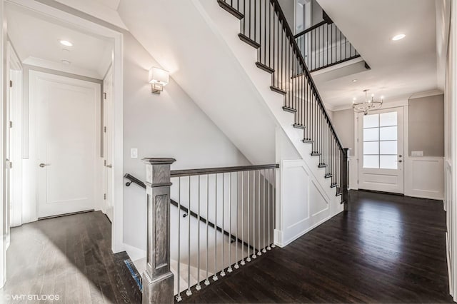 hallway featuring a chandelier, a decorative wall, wood finished floors, an upstairs landing, and crown molding