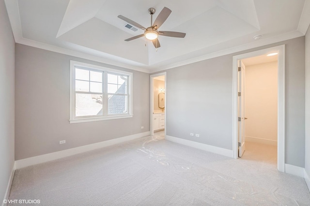 unfurnished bedroom featuring ensuite bathroom, visible vents, baseboards, a tray ceiling, and crown molding