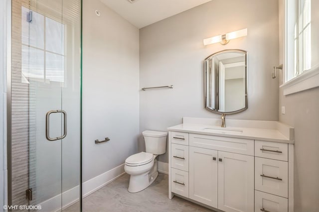 full bath featuring baseboards, a shower stall, toilet, and vanity