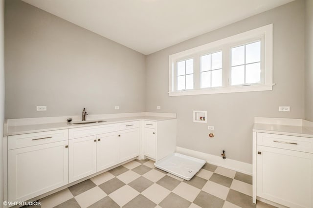 laundry room with washer hookup, light floors, hookup for a gas dryer, cabinet space, and a sink