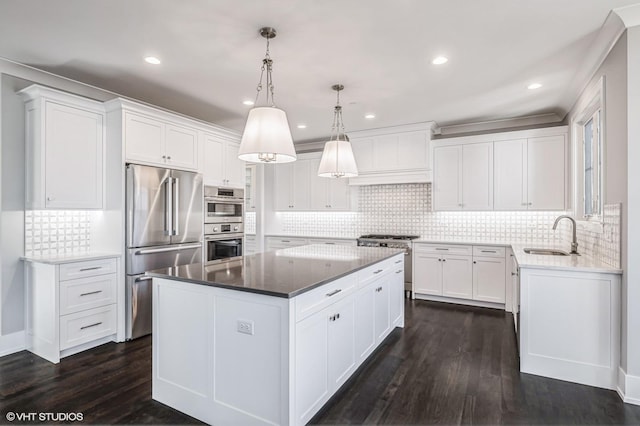kitchen with dark wood-style floors, high end appliances, white cabinets, a sink, and a kitchen island