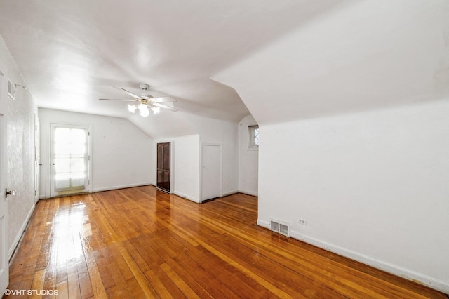 bonus room with wood-type flooring, visible vents, vaulted ceiling, and baseboards