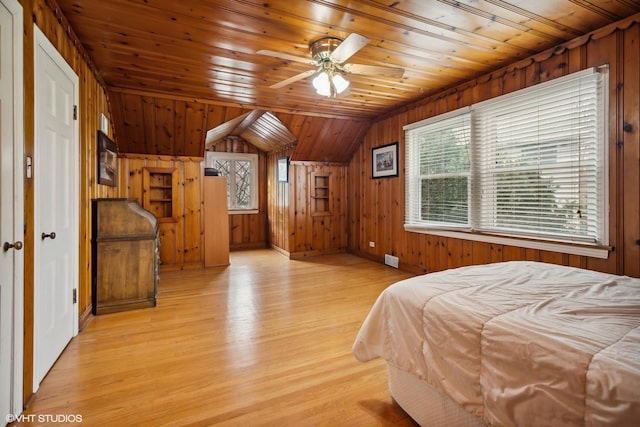 bedroom featuring lofted ceiling, light wood finished floors, wood ceiling, and wooden walls