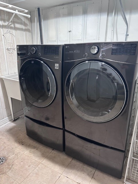 laundry room with light tile patterned flooring and washer and clothes dryer