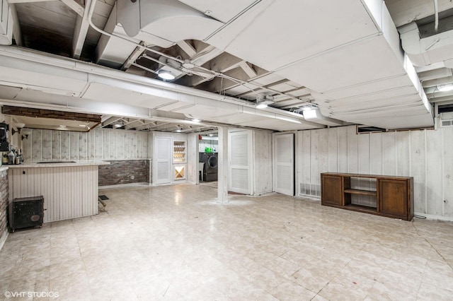 finished below grade area featuring wooden walls, washer and clothes dryer, and tile patterned floors