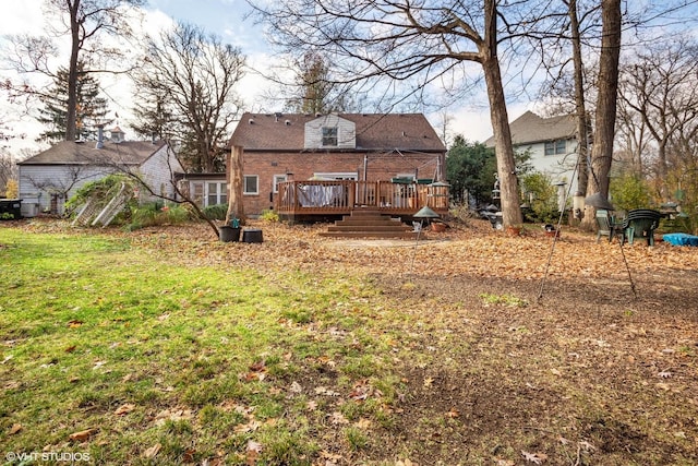 rear view of property featuring brick siding, a lawn, and a wooden deck