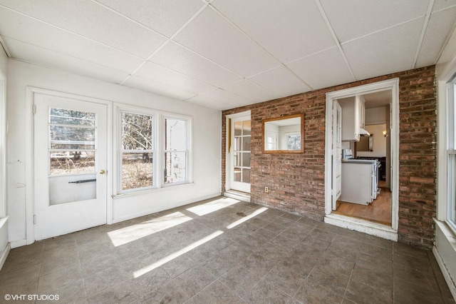 spare room with a paneled ceiling and brick wall