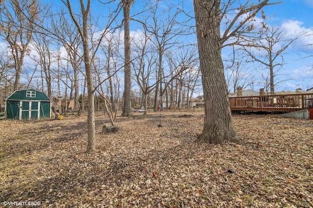 view of yard with a storage shed, a deck, and an outbuilding