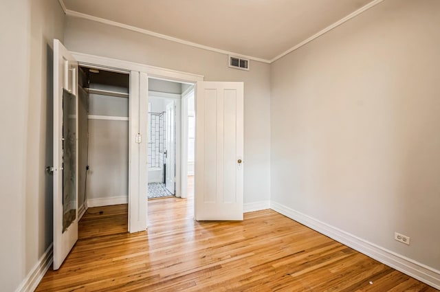 unfurnished bedroom featuring baseboards, light wood-style flooring, visible vents, and crown molding