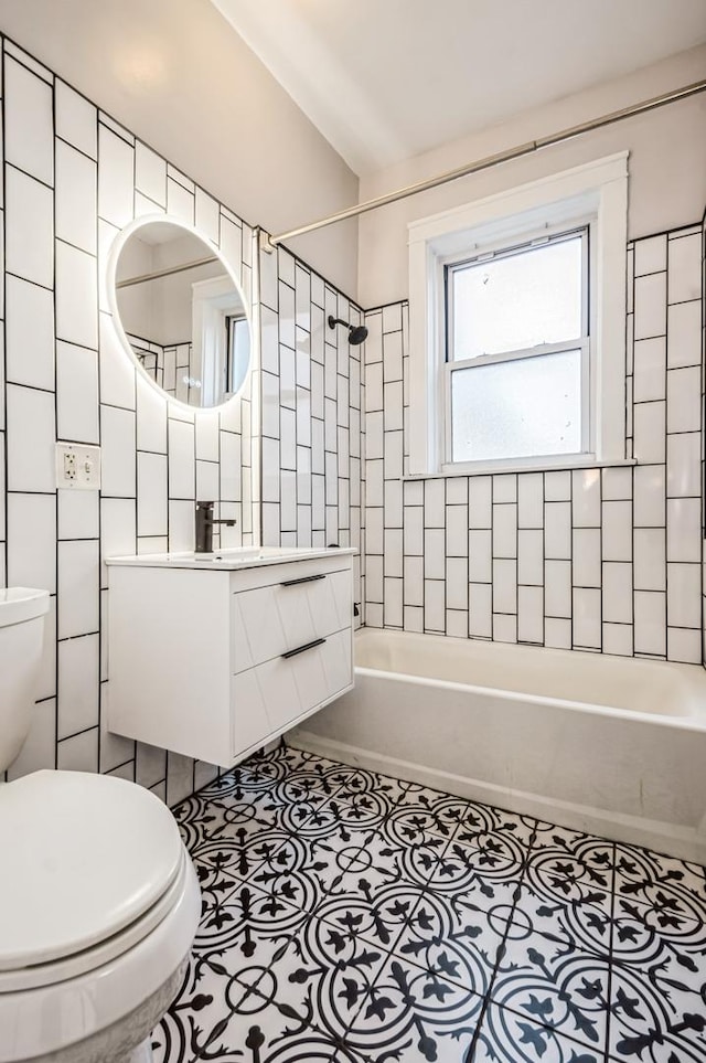 bathroom featuring shower / washtub combination, tile walls, toilet, vanity, and tile patterned floors