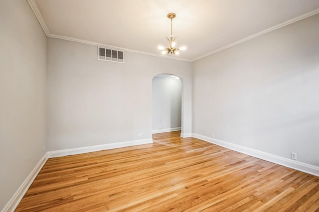 empty room with arched walkways, a notable chandelier, light wood finished floors, visible vents, and ornamental molding