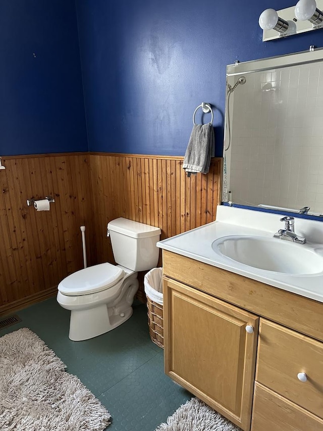 bathroom with visible vents, a shower, wainscoting, toilet, and vanity