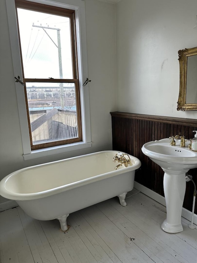 bathroom featuring hardwood / wood-style floors, a soaking tub, and a sink