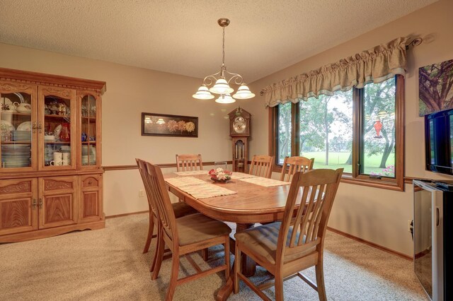 dining area featuring light carpet, baseboards, a chandelier, and a textured ceiling